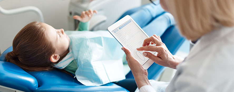 Hygienist using tablet with patient